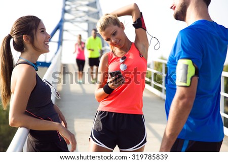 Outdoor portrait of running people having fun in the park with mobile phone.