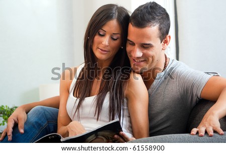 Portrait of happy  couple sitting on couch and reading a magazine