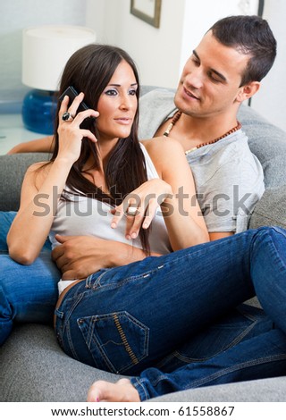 Portrait of happy  couple sitting on couch and talking on mobile phone