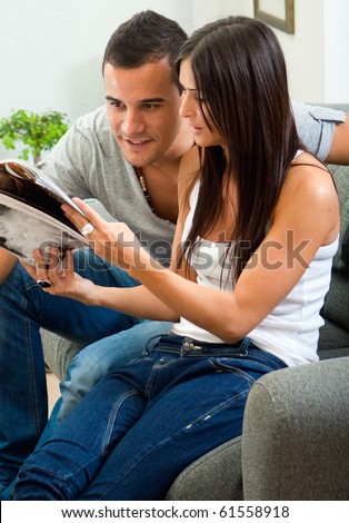 Portrait of happy  couple sitting on couch and reading a magazine