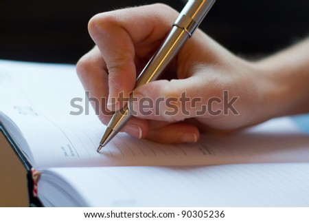 Woman hand writes on a paper