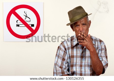 A senior citizen pays scant regard to a non-smoking sign.