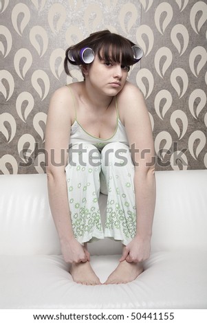 young adult girl with hair rollers sitting at white sofa