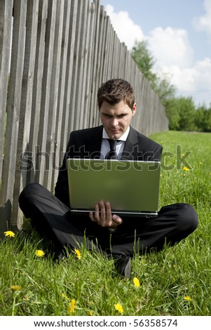 businessman in lotus pose working on laptop in country
