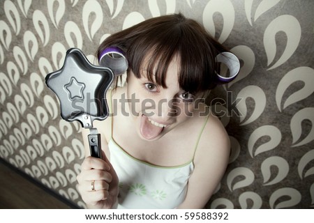 young adult girl with  frying pan star and hair rollers have fun