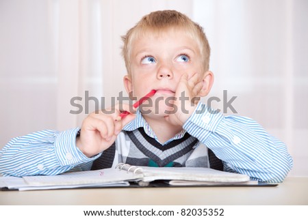 student sitting at a desk with a notebook and thinking how to do the job. boy with a thoughtful face