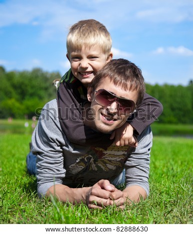 father with his son lying on the grass in the park, arm in arm