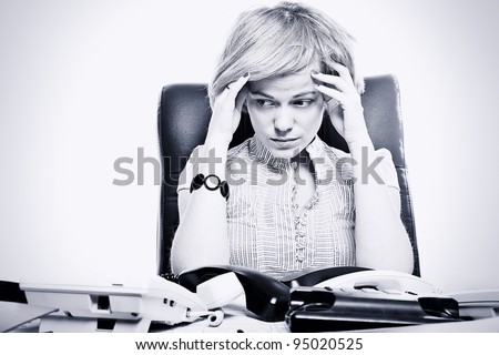 Portrait of business woman sitting at a desk in the office with many telephone with sad face, toned image