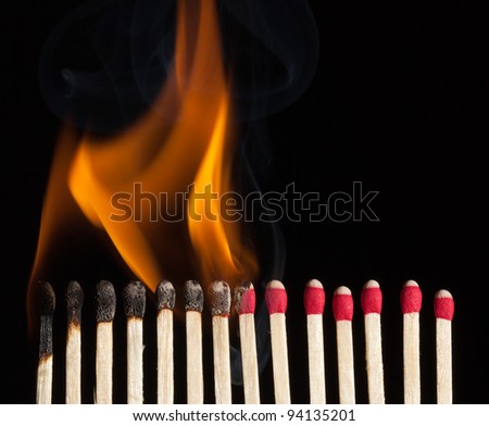 A line of red safety matches showing burnt out matches on the left , through burning matches, ignition, and unused ones on the right.