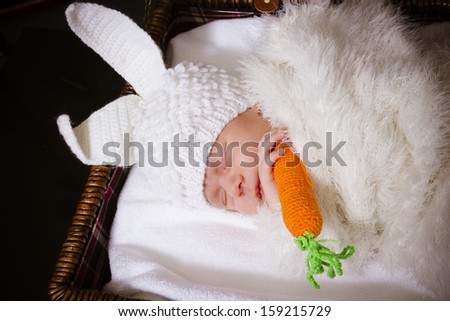 the sleeping baby in a suit of a rabbit with carrot