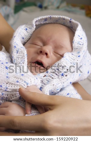 the baby dressed in a jacket sleeps at mother on hands