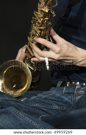close-up  cross-legged young jazz man plays a saxophone