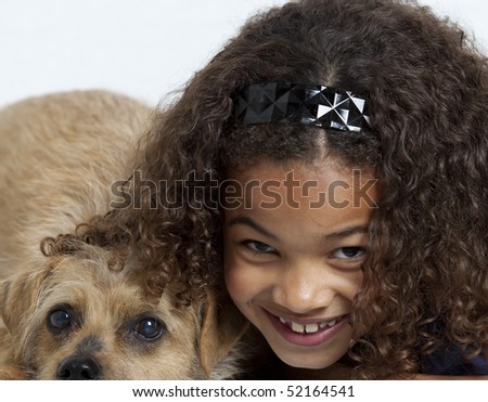 Portrait of a young girl with dreadlocks and frizzy hair, hugging a small dog. White background.