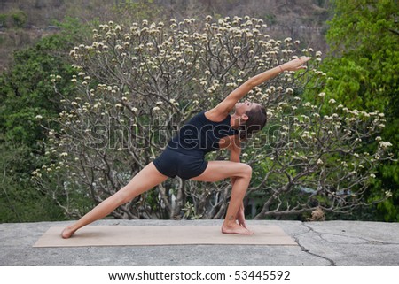 Female yoga teacher executing postures (asanas) at an old hotel in Rishikesh, India.