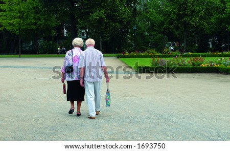 Older couple walking in the park from behind