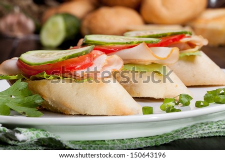 Three small sandwiches with ham and vegetables.