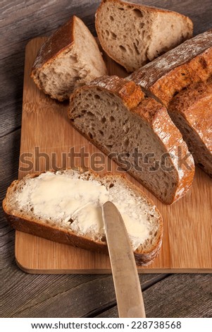 A slice of bread with butter on a chopping board.