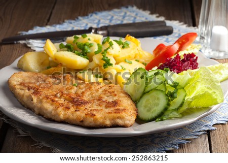 Fried pork chop with potatoes and vegetable salad.