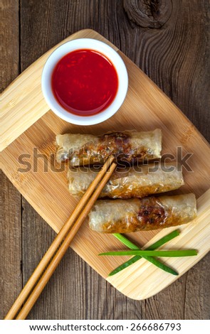 Fried spring rolls with vegetables on a wooden table.