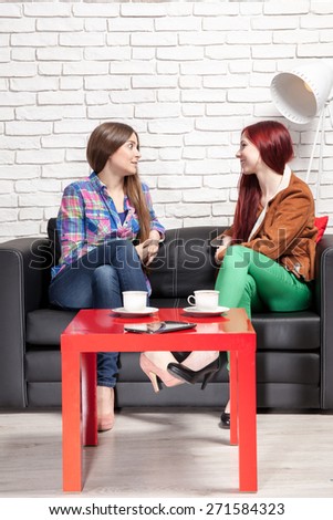 Two women chatting over coffee at home.