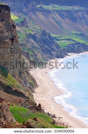 Sandy beach in a secluded cove under rocks (vertical landscape)