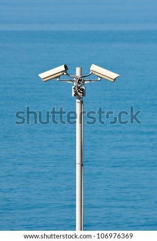 Two CCTV surveillance cameras on the sea background