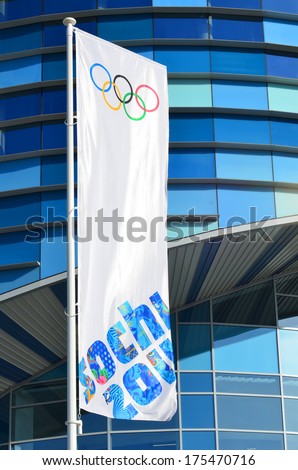 SOCHI, RUSSIA - FEBRUARY 7, 2014: Olympic flag with the symbol of the Sochi 2014 in front of the Ice rink for figure skating IcebergÃÂ in Olympic park