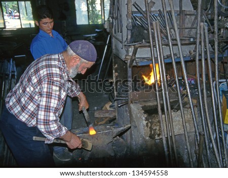 YUSUFELI, TURKEY - JULY 26: Country blacksmith with an assistant in his smithy on  July 26, 2000 in eastern Turkey. Folk artists and culture are typical of the Black Sea region.