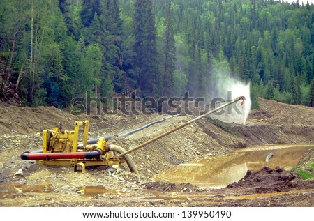 CHICKEN CREEK, ALASKA, USA - JULY 24: Gold Dredge, small mine operator wash gold off rock and sand in Chicken Creek on July 24, 1997 in Alaska, USA.