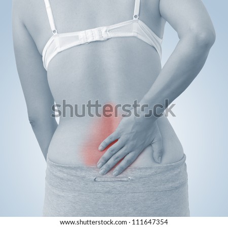 Acute pain in a woman back. Female from behind holding hand to spot of back pain. Concept photo with Color Enhanced blue skin with read spot indicating location of the pain.