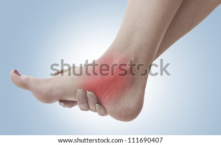 Pain in a woman ankle. Female holding hand to spot of ankle-ache. Concept photo with Color Enhanced skin with read spot indicating location of the pain.