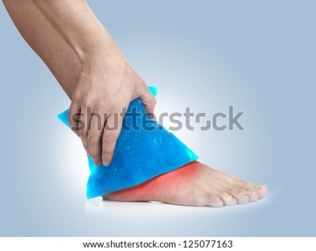 Cool gel pack on a swollen hurting ankle. Medical concept photo.  Color Enhanced skin with read spot indicating location of the pain.