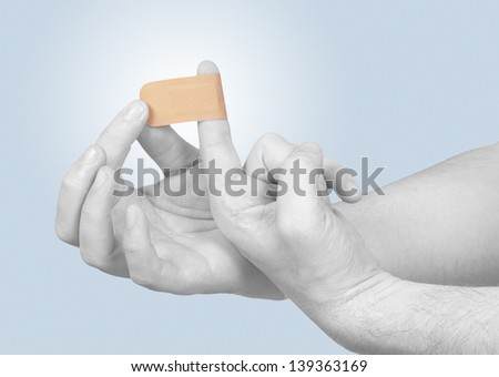Putting a small adhesive plaster on a finger.  Concept photo with Color Enhanced skin.