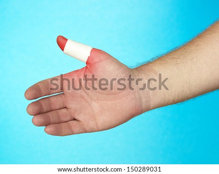 Adhesive bandage on finger tip. On blue background.