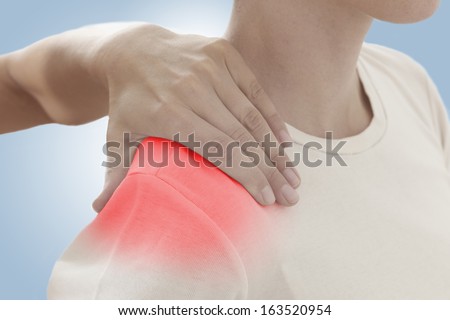 Acute pain in a woman shoulder. Female holding hand to spot of shoulder-aches. Concept photo with Color Enhanced blue skin with read spot indicating location of the pain. On light blue background.