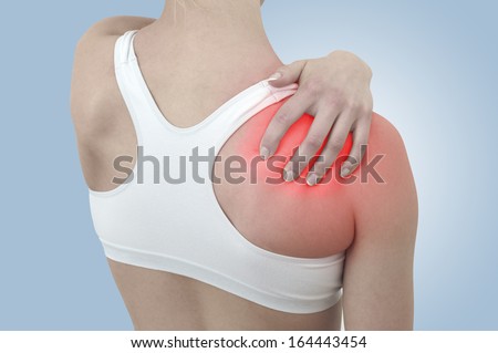 Acute pain in a woman shoulder. Female holding hand to spot of shoulder-aches.