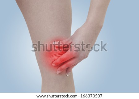 Acute pain in a woman  knee. Female holding hand to spot of knee-aches. Concept photo with Color Enhanced blue skin with read spot indicating location of the pain.
