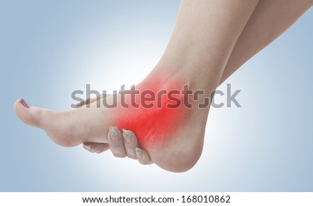 Pain in a woman ankle. Female holding hand to spot of ankle-ache. Concept photo with Color Enhanced blue skin with read spot indicating location of the pain.