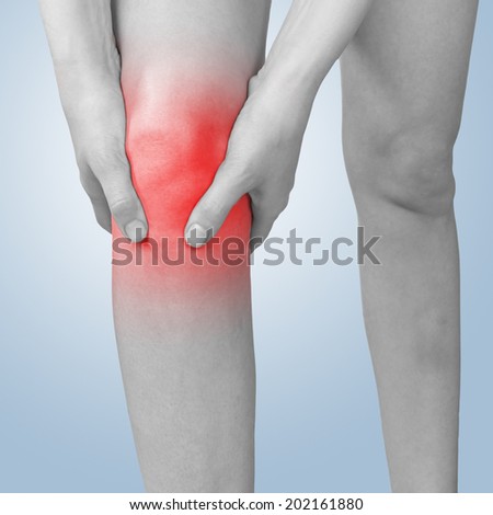 Acute pain in a knee. Female holding hand to spot of knee-aches.