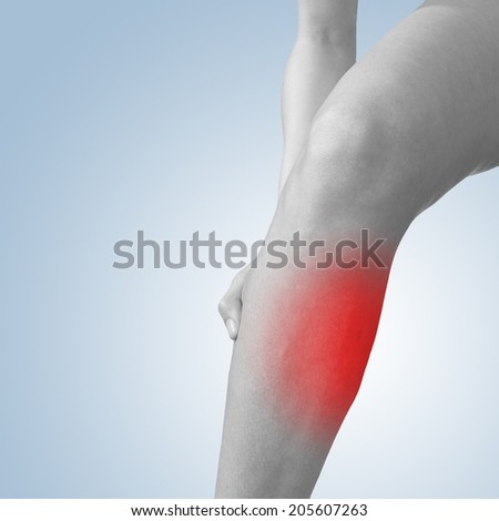 Acute pain in a calf. Woman holding hand to spot of calf-aches.