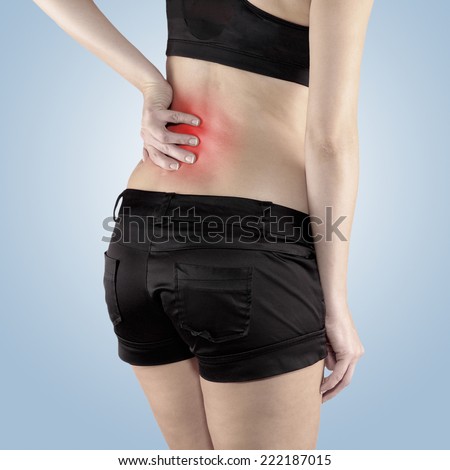 Back pain. Athletic woman in black sportswear standing and rubbing the muscles of her lower back, cropped torso portrait.