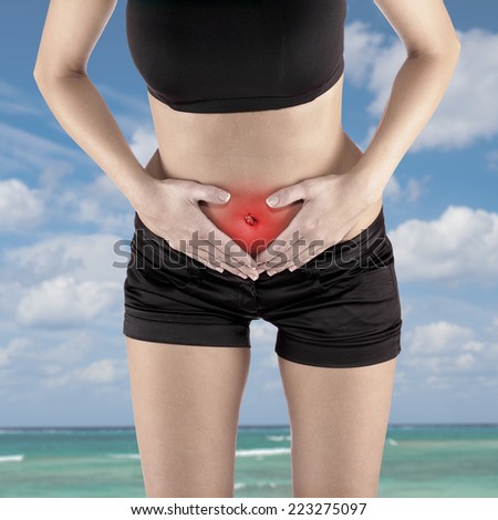 Woman\'s hands on stomach pain concept.
