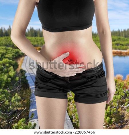 Woman\'s hands on stomach pain concept. Autumn Park Backgroun