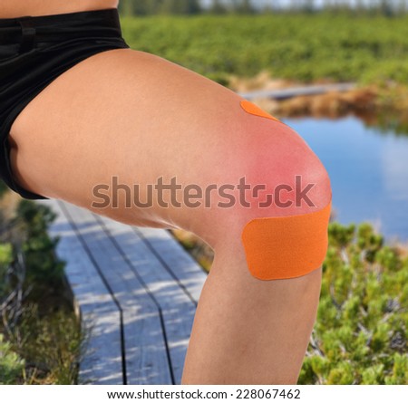 Injured knee treated with tape therapy. Autumn Park Backgroun