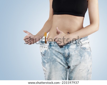 Woman shows her weight loss by wearing an old jeans. Weight loss concept.