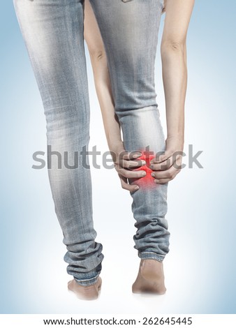 Woman massaging her painful leg calf. Joint injury or disease concept.