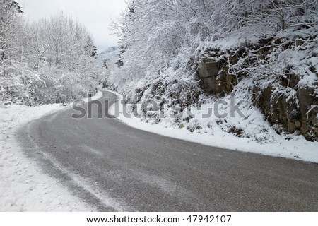 A curve in an empty, icy road through the mountains during winter