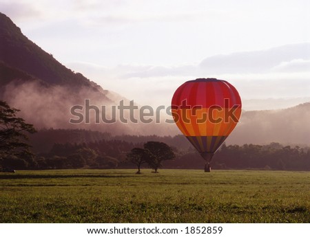 A colorful hot air balloon landing in a misty morning meadow