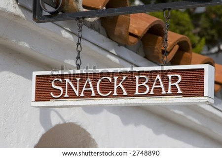 A snack bar sign in front of a Spanish style building