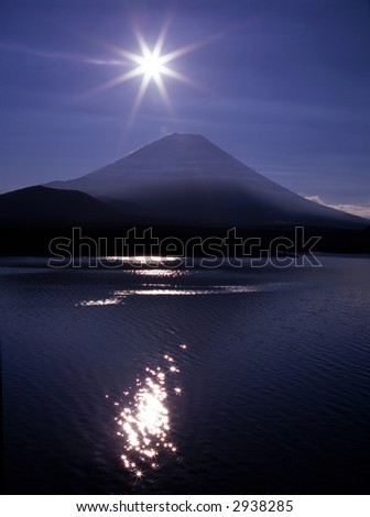 Mount Fuji with the Sun and its glittering reflections in a mountain lake
